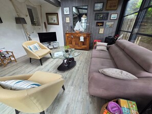 Un salon avec un canapé, un fauteuil et une table basse en verre.