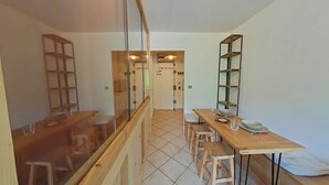 Eine moderne K üche mit Holzausstattung, einem Esstisch mit Stühlen und einer Glastrennwand.