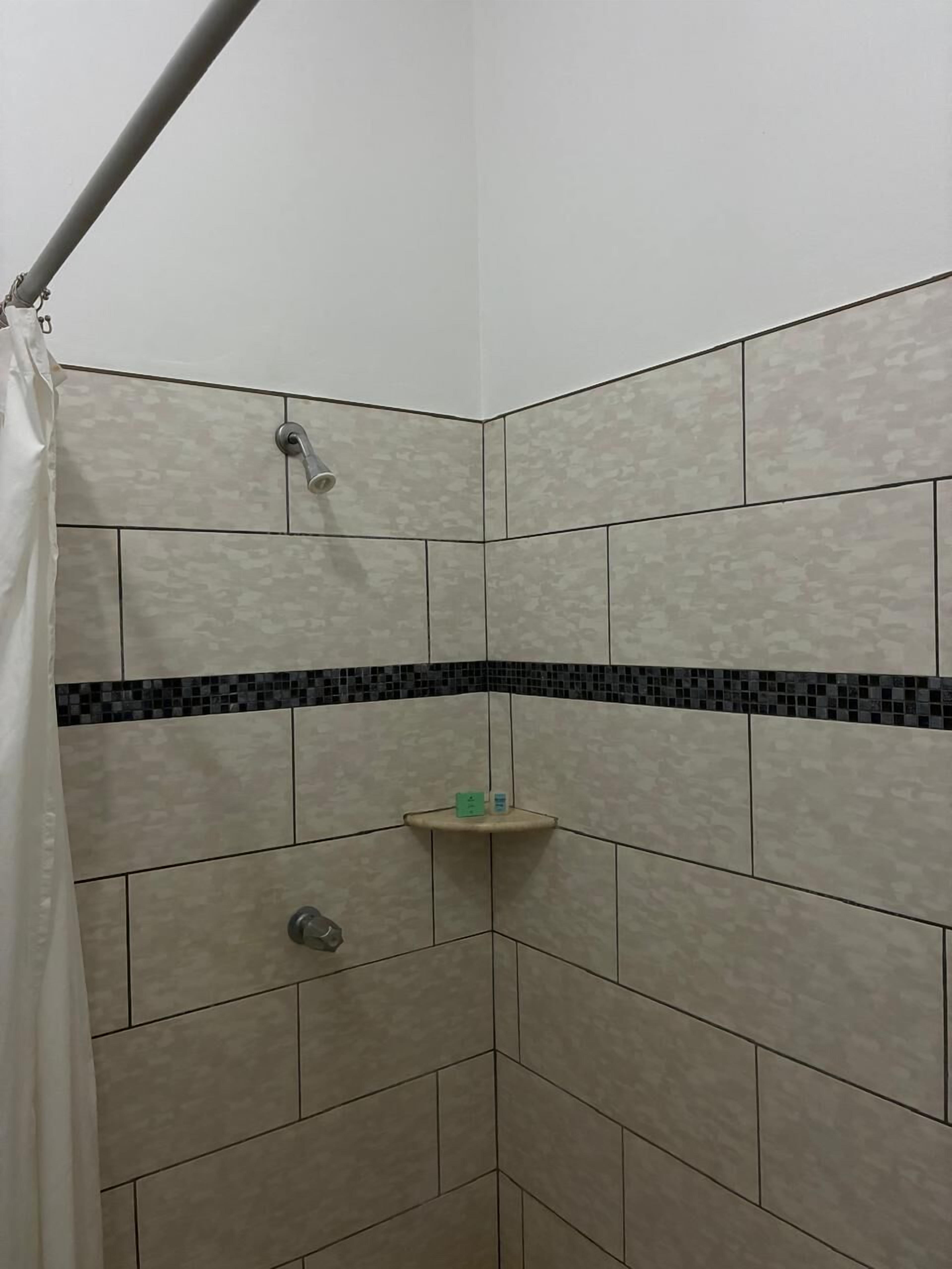 A shower area with beige tiles, a black and beige border, and a showerhead.