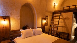 A bedroom with a large bed, wooden headboard, and a ladder leaning against the wall. - Lemon Cave Suites And Coffee House (Avanos)