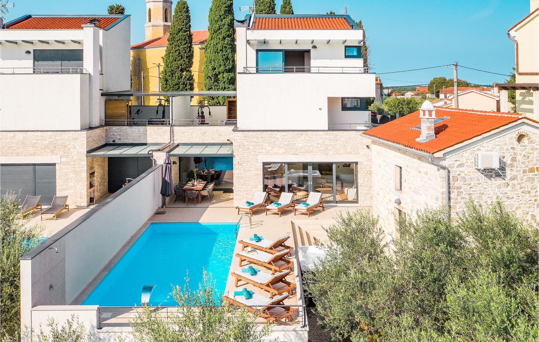 Una villa moderna con piscina, area relax esterna e facciata in pietra.
