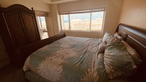 Un dormitorio con cama, armario de madera y ventana con vistas a edificios.