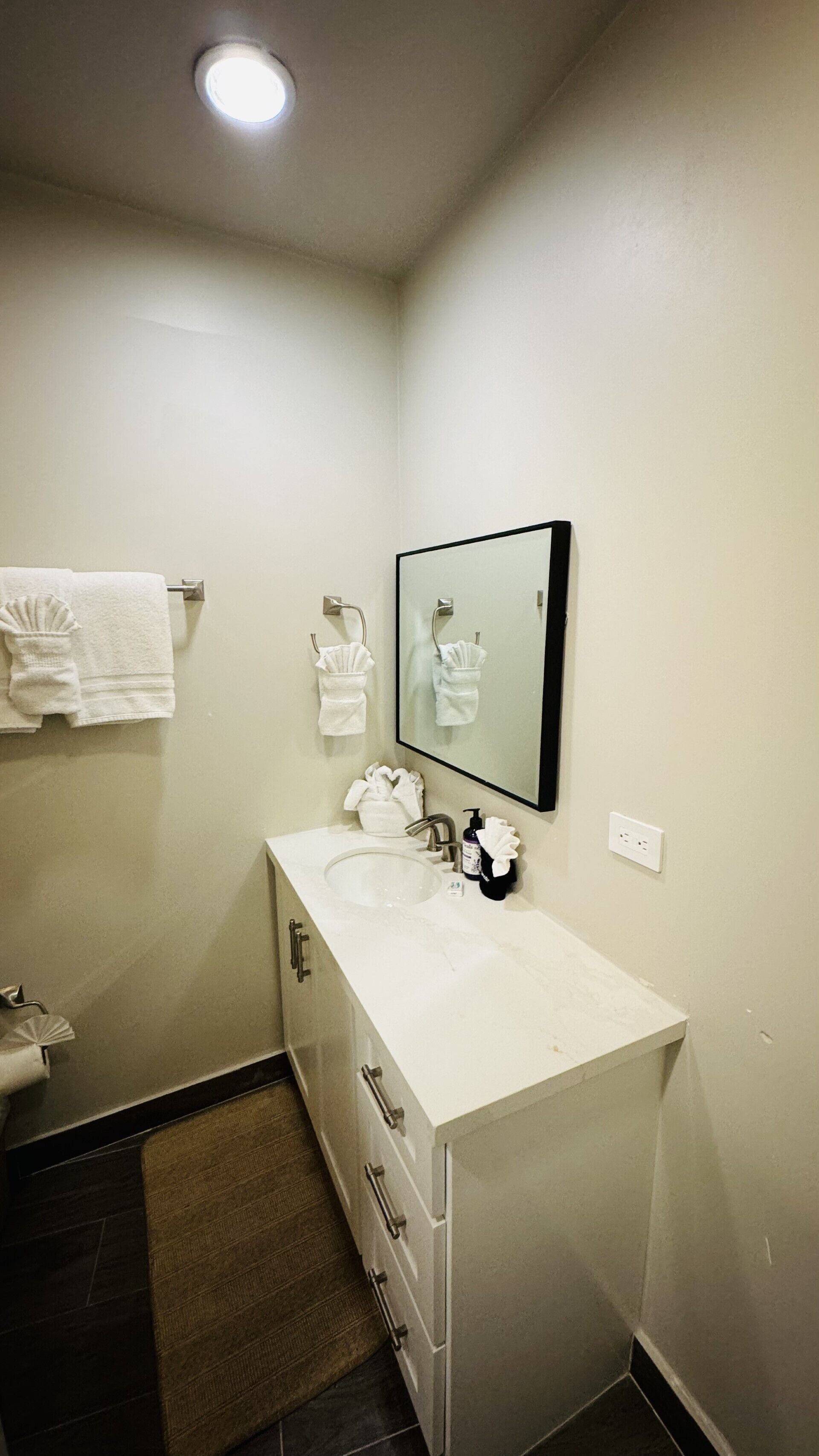 Un baño pequeño con un lavamanos blanco, un espejo y un perchero para toallas.