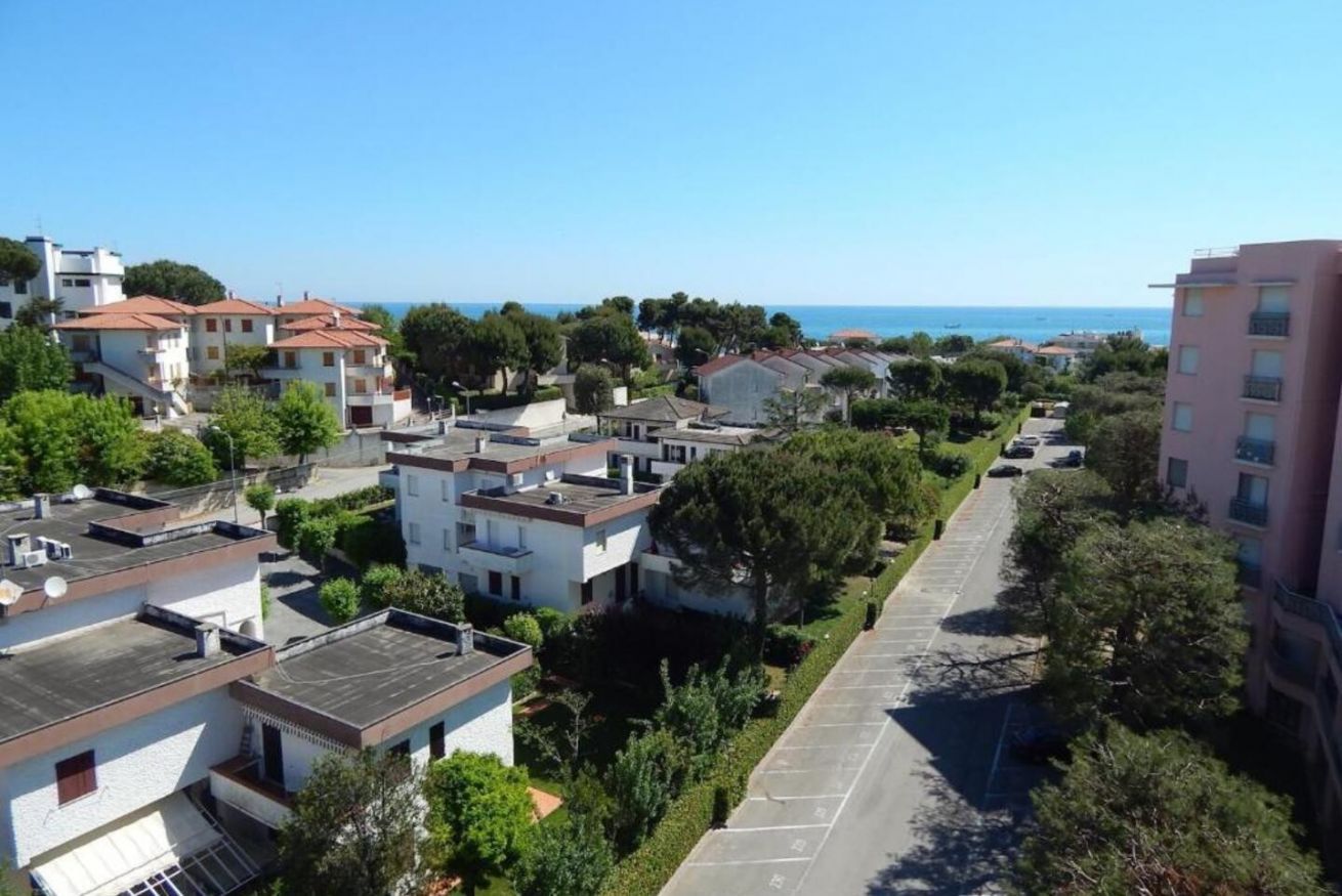 Zona residencial com edifícios modernos, um parque de estacionamento e vista clara para o mar.