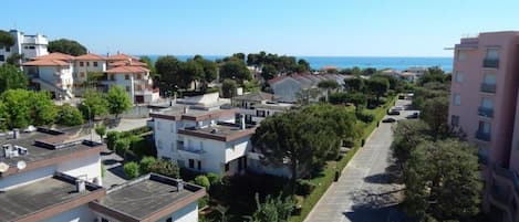 Zona residencial com edifícios modernos, um parque de estacionamento e vista clara para o mar.