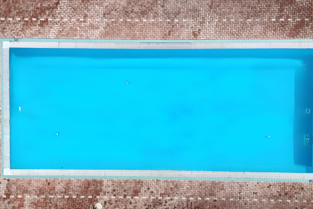 A rectangular swimming pool with a clear blue water surface, surrounded by a tiled wall.