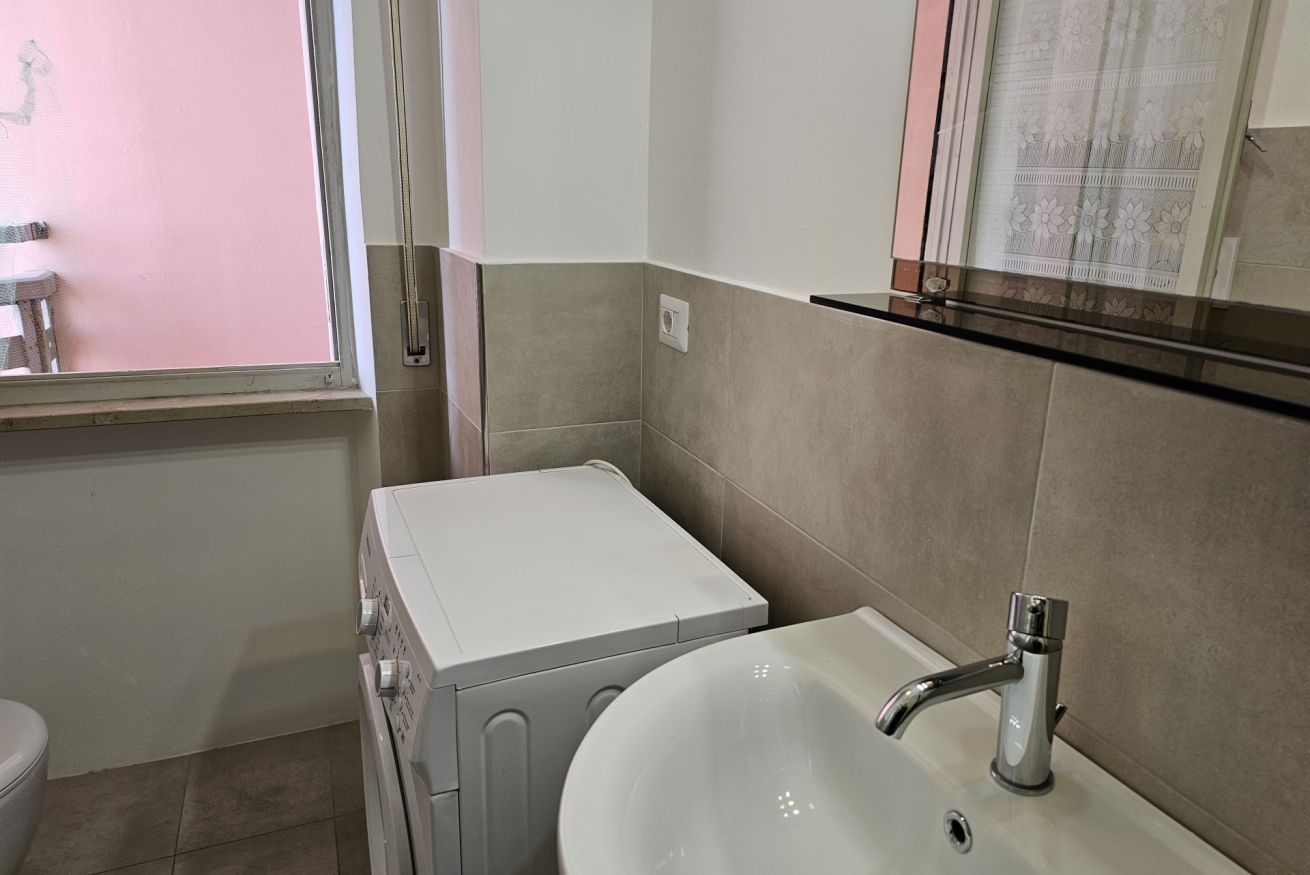 A bathroom with a white sink, a mirror, and a window.