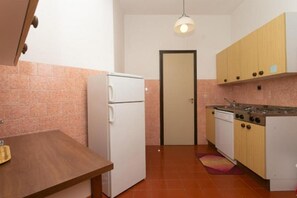 A compact kitchen with a refrigerator, stove, and wooden cabinets.