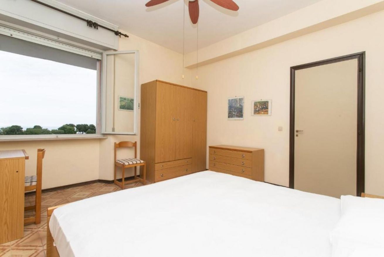 Een slaapkamer met een bed, een kledingkast, een bureau, een stoel en een raam.
