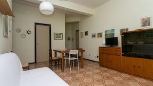 Una habitación con una cama, una mesa de comedor con sillas, un televisor y un armario.