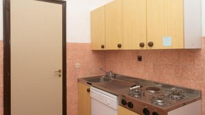 Una cocina compacta con lavavajillas, estufa de cuatro quemadores y armarios de madera.