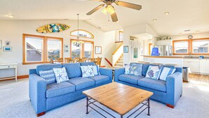 A spacious living room with two blue sofas, a wooden coffee table, and a ceiling fan.