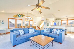 A spacious living room with two blue sofas, a wooden coffee table, and a ceiling fan. - Bailey's Irish Dream | 630 ft from the beach | Private Pool, Hot Tub | Nags Head (Nags Head)