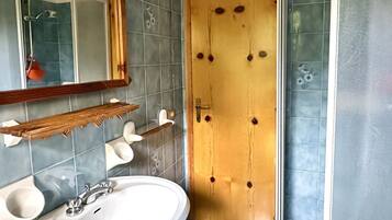 A bathroom with a wooden door, a mirror, a sink, and a shower.