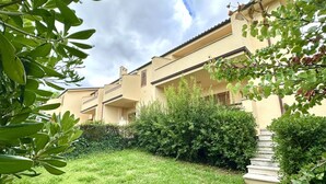 Un immeuble doté de plusieurs balcons, d’un espace verdoyant et d’un escalier menant à l’entrée.