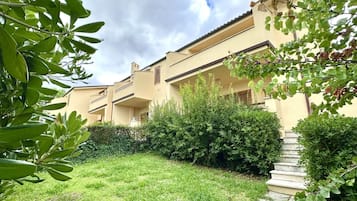 Un edificio con diversi balconi, una zona verde e una scalinata che conduce all'ingresso.