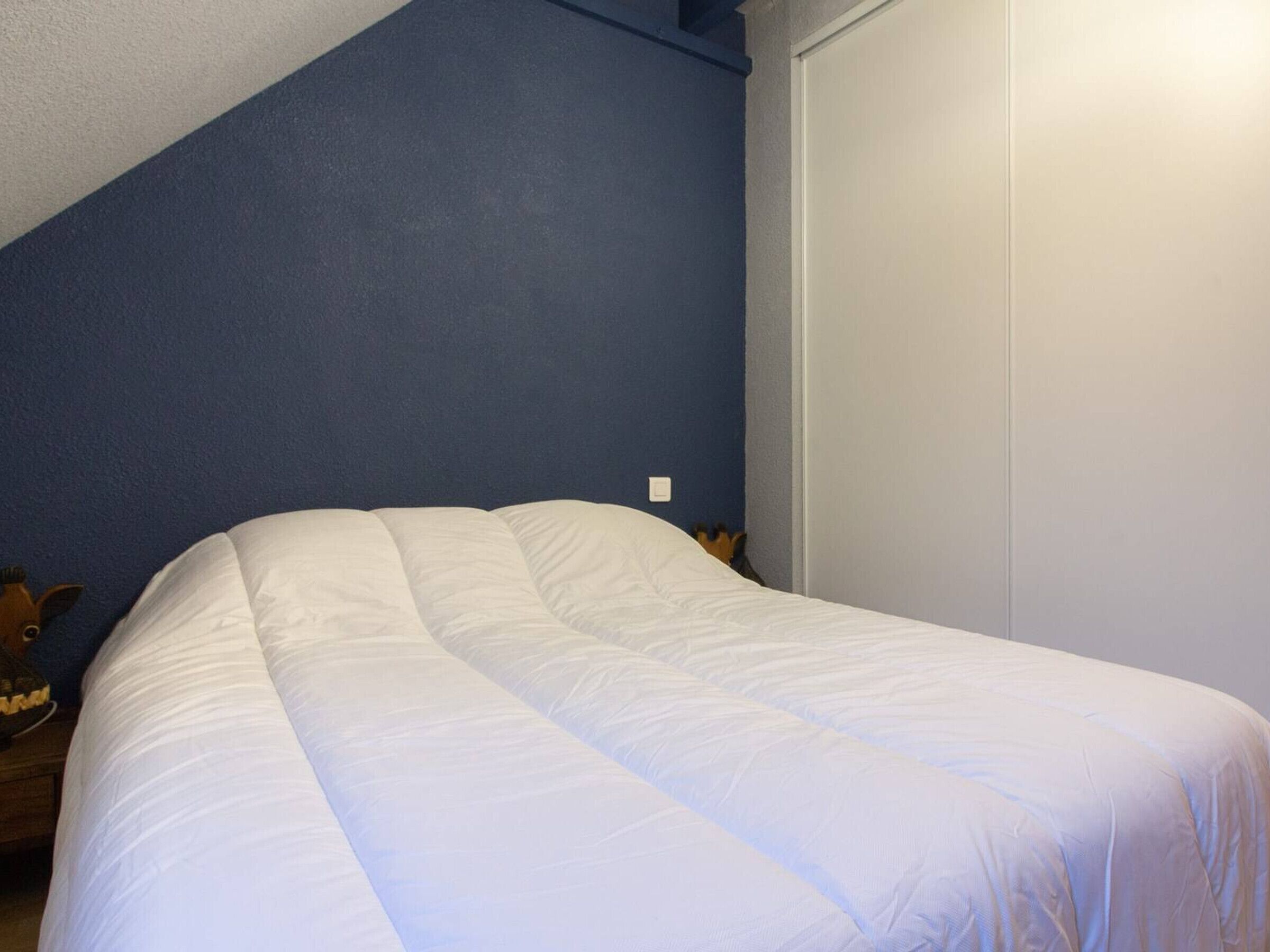 Une chambre à coucher avec un lit, un mur bleu et une porte blanche.