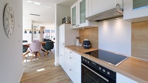 A modern kitchen with white cabinets, a wooden countertop, and a built-in oven. - NEW: Child-friendly holiday home, bicycles & handcart, 300m to the beach (Langeoog)
