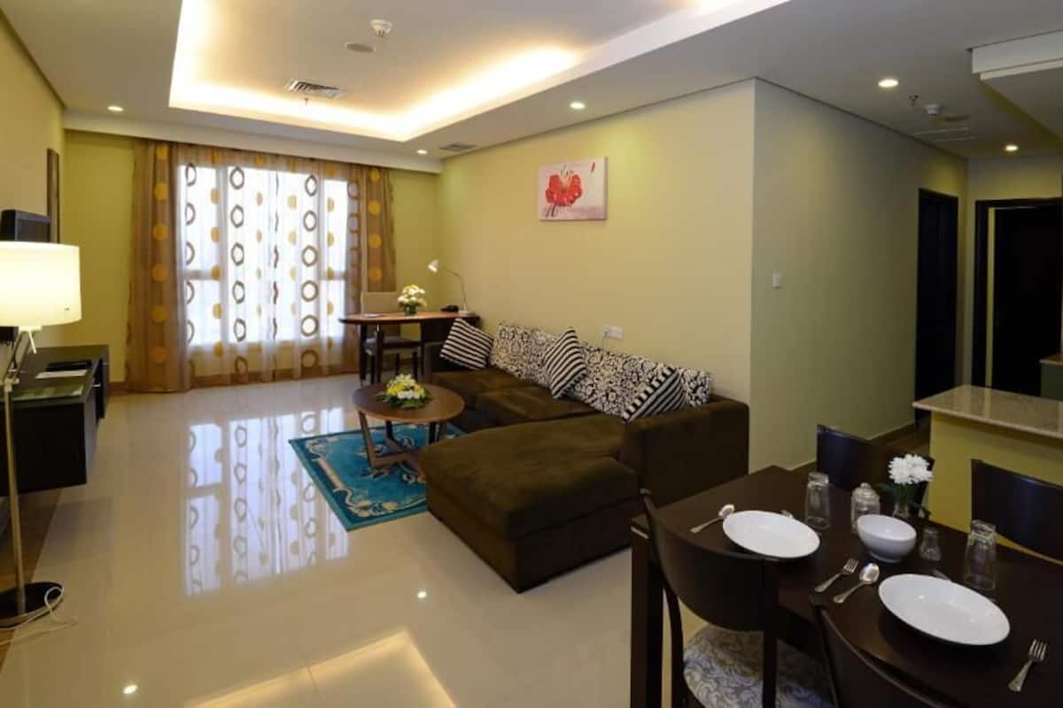 A modern living room with a sofa, dining table, and kitchen area.