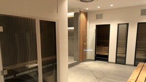 Moderni hotellihuone, jossa on suuri puinen pöytä, liukuovi ja sisäänrakennettu sauna.