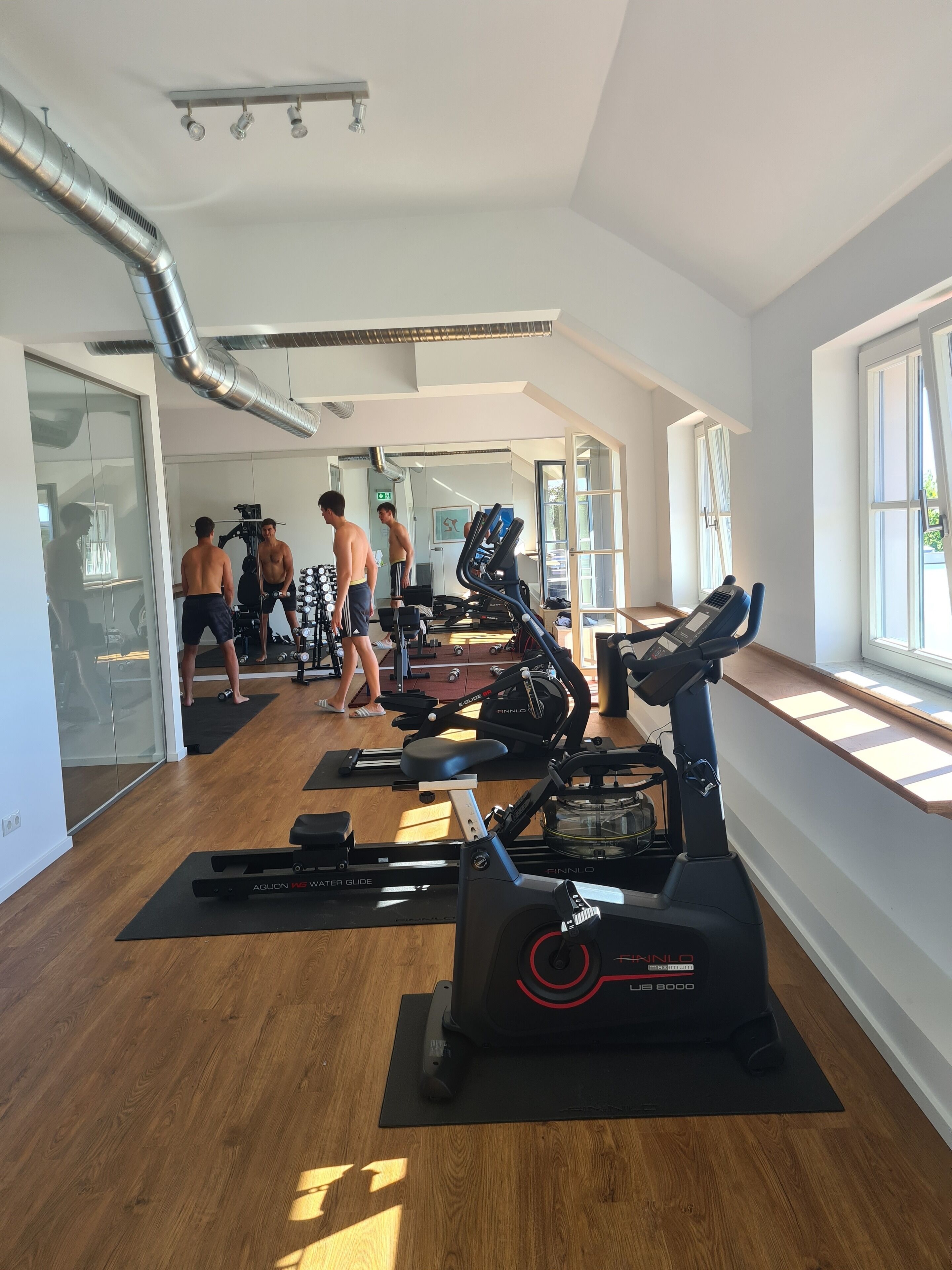 A gym with cardio machines, weightlifting equipment, and a large mirror.
