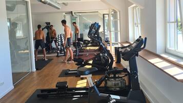 A gym with cardio machines, weightlifting equipment, and a large mirror.