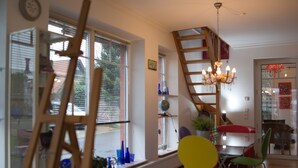 A room with a wooden ladder, a chandelier, a yellow chair, and a red table. - Vacation luck hit (Meppen)