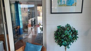 A wicker chair with a blue cushion, a potted tree, and a framed picture on the wall. - Vacation luck hit (Meppen)