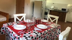 A dining area with a table set for two, a kitchen in the background, and a door leading to another room. - Deluxe Apartment with Breakfast Included. (Villa Gral. Belgrano)