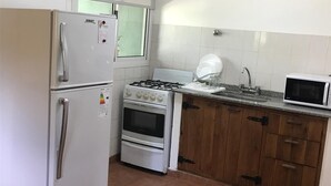 A compact kitchen with a refrigerator, stove, oven, microwave, and wooden cabinets. - Deluxe Apartment with Breakfast Included. (Villa Gral. Belgrano)