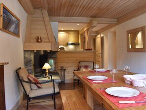 Ein gemütliches Holzinterieur mit Kamin, Esstisch für zwei Personen und einer komfortablen Sitzecke.