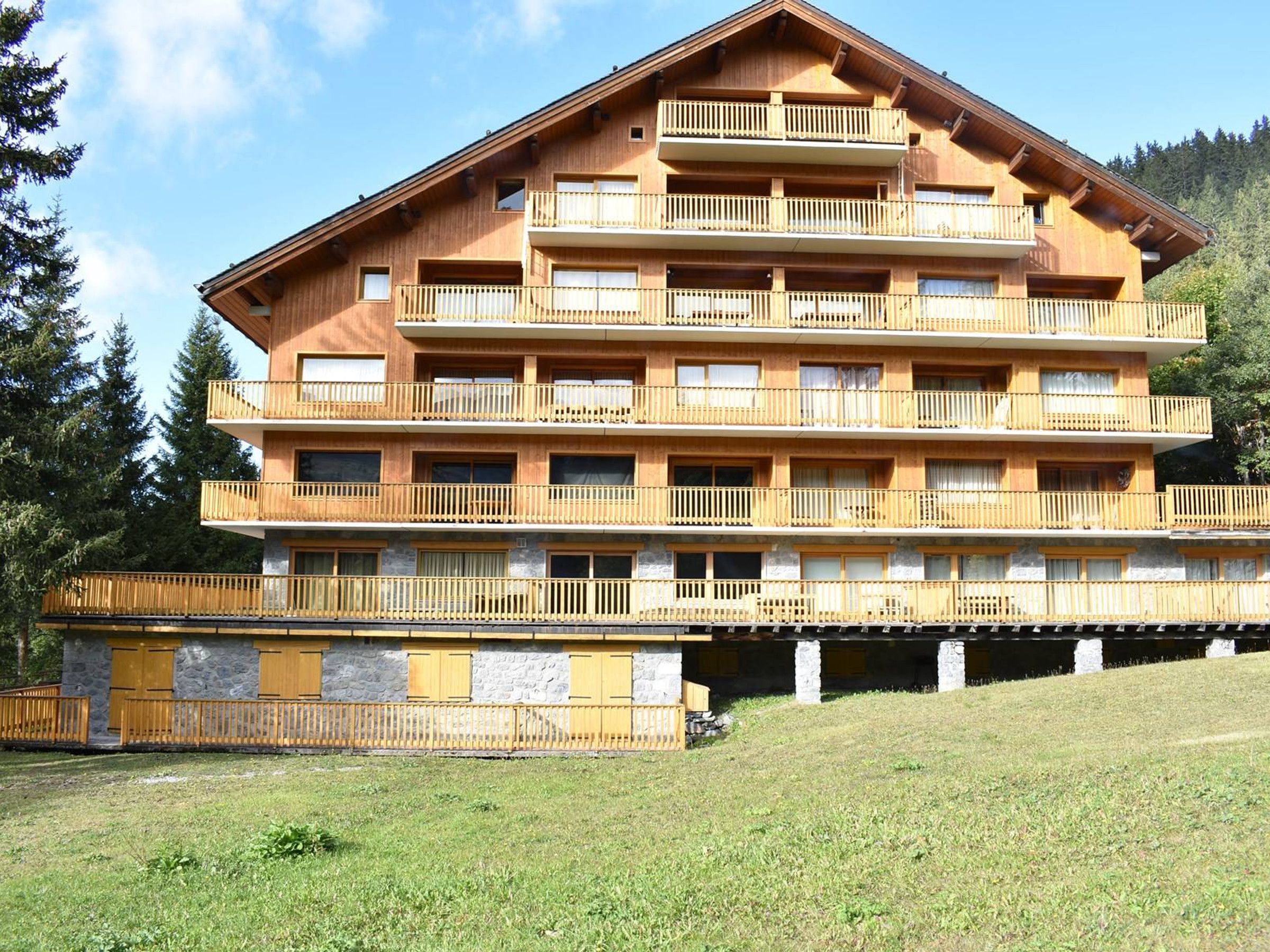 Un immeuble en bois à plusieurs étages, doté de balcons, qui ressemble probablement à un hôtel ou à un complexe touristique.