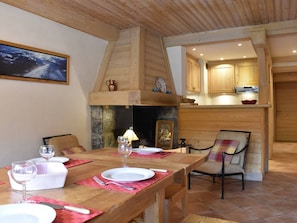 A dining area with a wooden table set for two, a fireplace, and a kitchen visible through an open doorway. - Cozy apartment near slopes - 6 guests (Méribel)