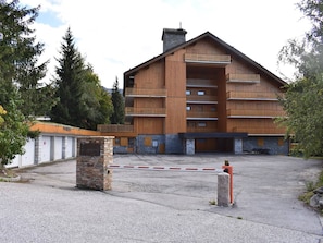 A multi-story wooden building with balconies, a stone entrance, and a gated driveway. - Cozy apartment near slopes - 6 guests (Méribel)