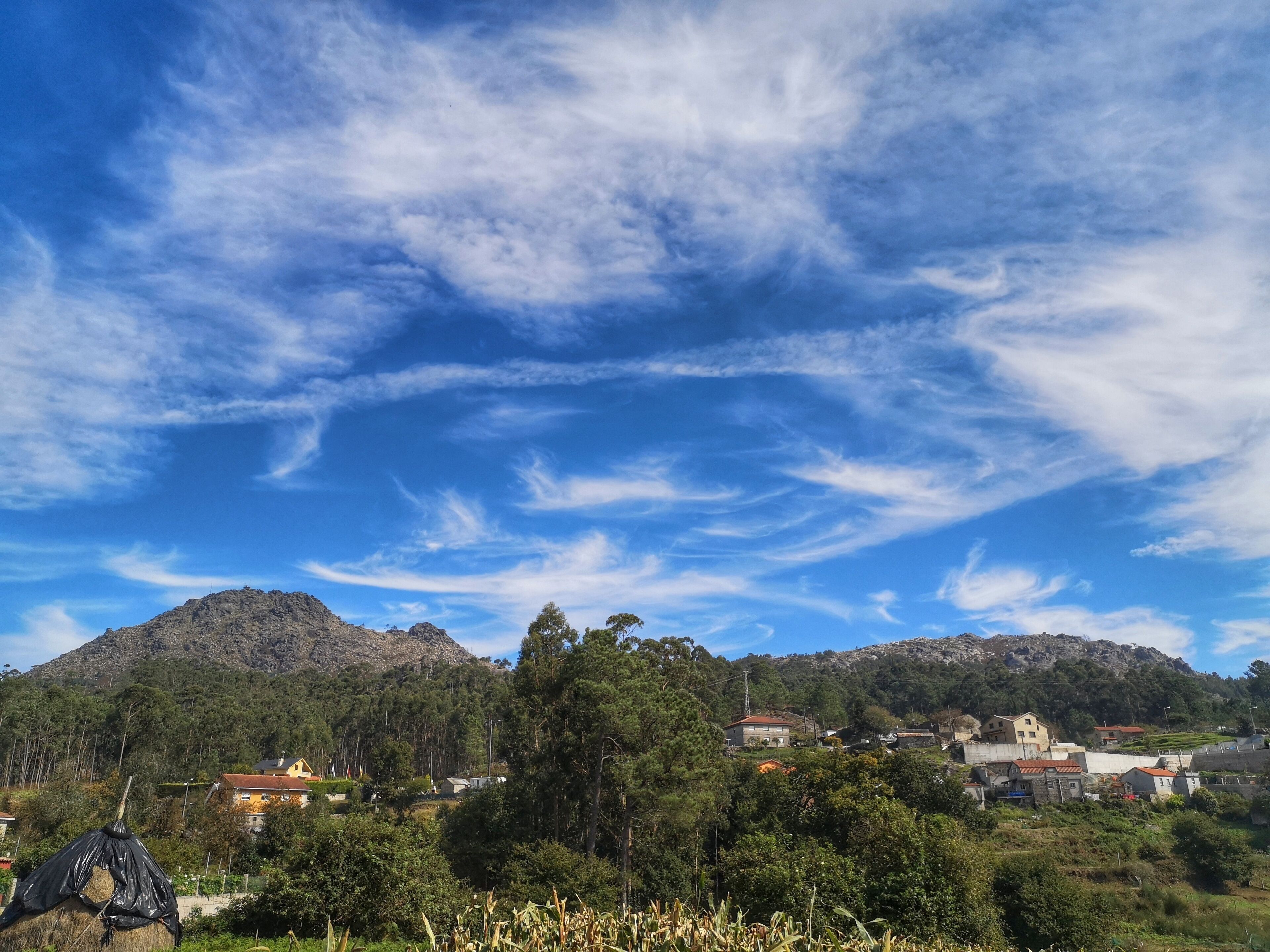 Paisaje rural con una montaña, casas y cielo despejado.