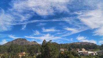 Paisaje rural con una montaña, casas y cielo despejado.