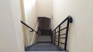 Eine schmale Treppe mit schwarzen Handläufen und einem Metallgeländer auf einer Seite.