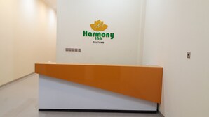 Ein Empfangstresen mit einem Logo mit der Aufschrift "Harmony Inn BELITUNG" und einer Reihe von Knöpfen darunter.