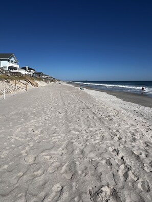 A beach with a wooden staircase leading to a building with multiple balconies.