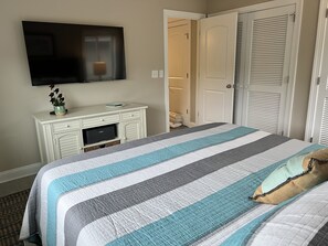 Un dormitorio con una cama, un televisor montado en la pared, un aparador y un armario.