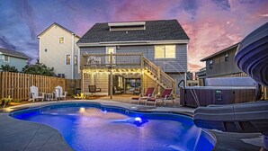 A backyard with a swimming pool, deck chairs, and a hot tub. - Your Ultimate  Retreat – Steps from Beach with PVT Heated Pool, Slide & Hot Tub! (Surf City)