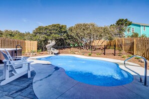 Un patio trasero con piscina, tobogán y valla de madera.