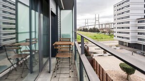 Varanda com área de estar externa e vista para uma ponte e prédios.