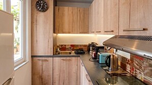 Une cuisine moderne avec des meubles en bois, une cuisinière encastrée et une horloge au mur.