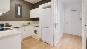 Une cuisine moderne équipée d’un lave-linge, d’un réfrigérateur et d’une fenêtre située au-dessus de l’évier.
