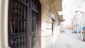 Une entrée d’immeuble avec un grand portail en métal et un petit auvent.