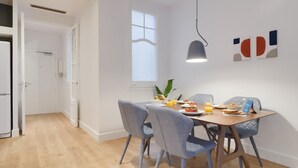Un espace de salle à manger moderne, avec une table en bois, des chaises à revêtement gris et une fenêtre en verre dépoli.