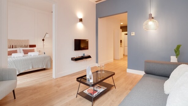 Un salon moderne avec un canapé, une table basse sur laquelle sont posés des magazines, un téléviseur et un mur d’accent bleu.