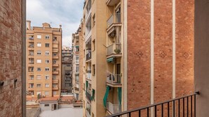 A multi-story residential building with balconies, a brick facade, and a visible rooftop area. - Sweett | Sepulveda 3B (Barcelona)