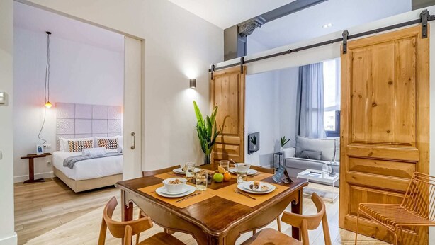 Een moderne hotelkamer met een houten eettafel, ontbijtset en een bed met een gestreept hoofdeinde.